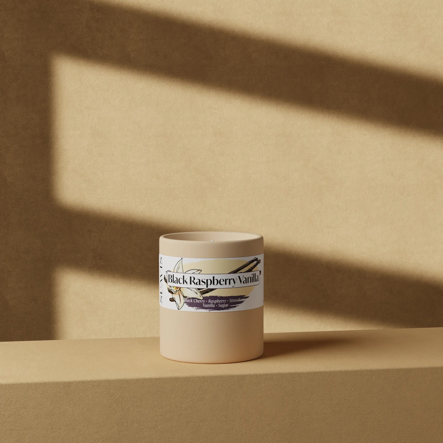 Black Raspberry Vanilla Scented Candle in a 12oz Cream Ceramic vessel in front of a wall.