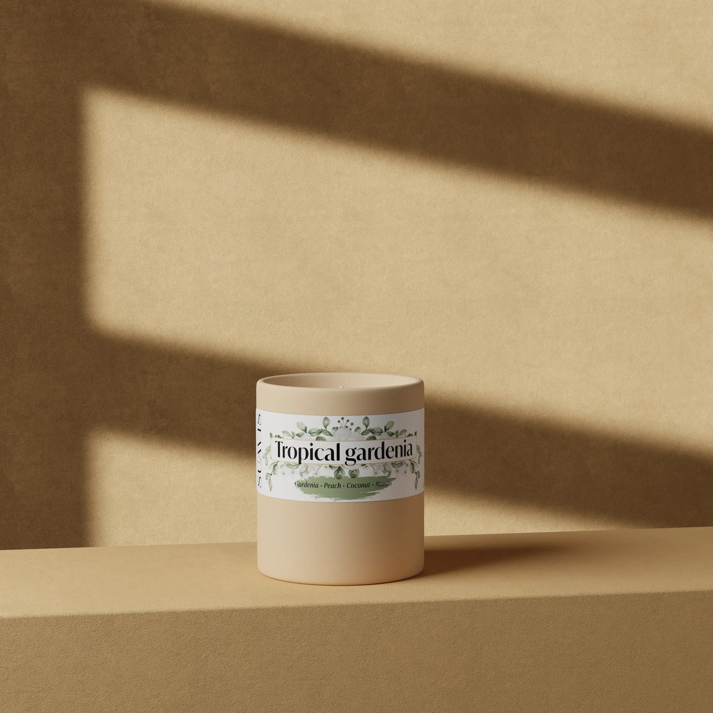 Tropical Gardenia Scented Candle in a 12oz Cream Ceramic vessel in front of a wall.