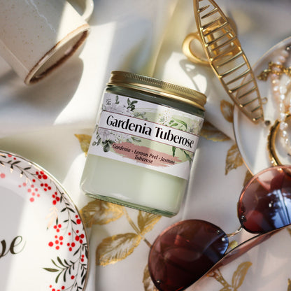 Jar of Gardenia Tuberose Candle on a decorative tablecloth with accessories around it