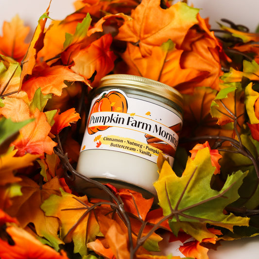 Jar of pumpkin farm morning candle surrounded by autumn leaves