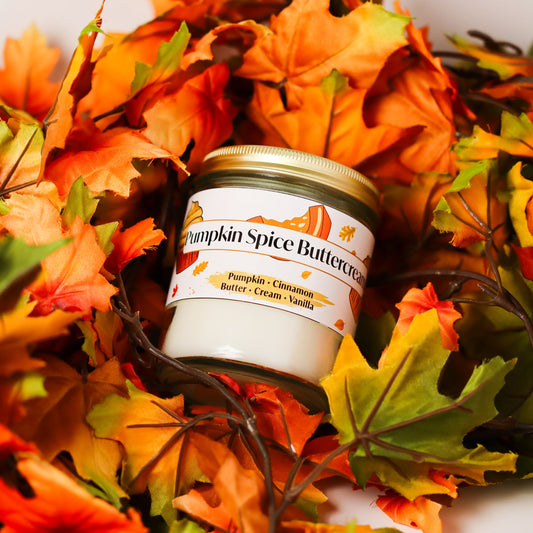 Jar of pumpkin spice buttercream candle surrounded by autumn leaves