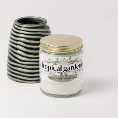 Tropical gardenia candle on a white background next to a green vase