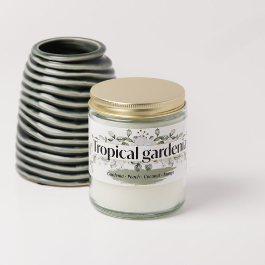 Tropical gardenia candle on a white background next to a green vase