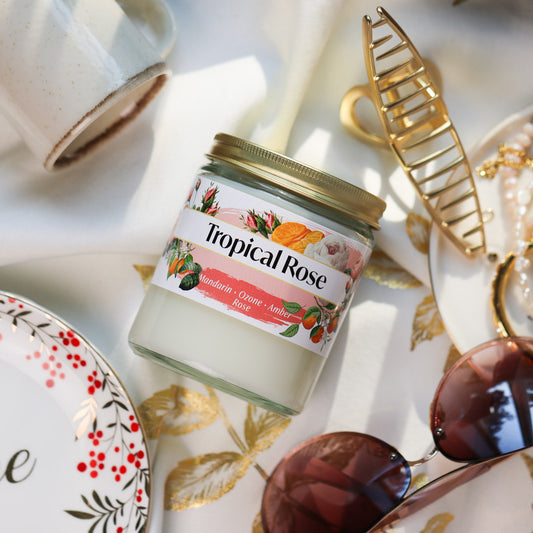 Jar of Tropical Rose Candle on a decorative tablecloth with accessories around it