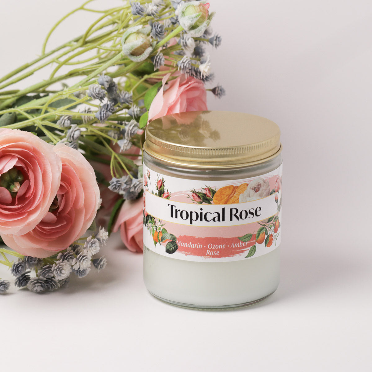 Tropical rose candle on a white background next to roses