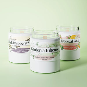 Three scented candles in glass vessels on a light green studio background